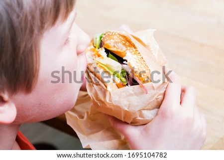 Child eating hamburger, boy with burger in hands