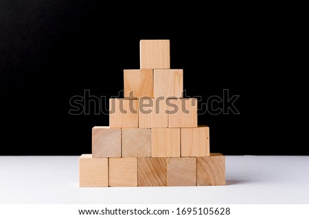 stacking wooden cubes on black background. Business concept on progress or building something.