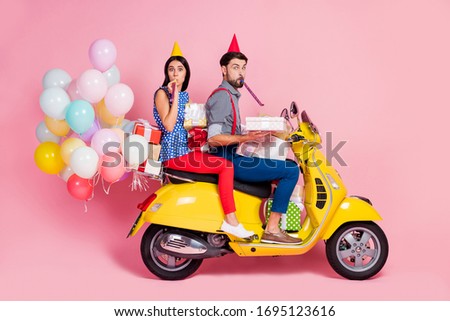 Full body profile side photo funny two people friends drive chopper deliver gift boxes whistle blower air baloons fly wear birthday cones shirt pants dotted retro red isolated pink color background