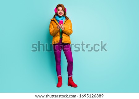 Full body photo of pretty traveler lady hold telephone searching map navigation wear trendy casual yellow overcoat scarf violet trousers shoes isolated teal color background