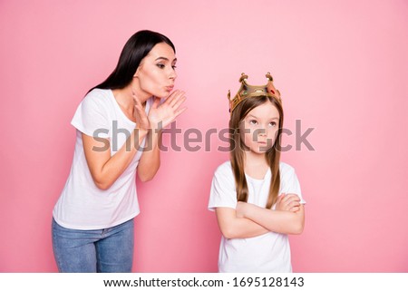 Photo of charming overjoyed mommy blowing kisses little angry spoiled daughter with crown on head boast person wear casual t-shirts jeans isolated pastel pink color background
