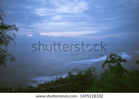 Beautiful blue sunset on the ocean with big waves and cliffs and cliffs. Bali island with its tropical and exotic nature. Sunrise over the sea and ocean. Phantom blue in sunset