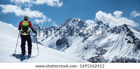 Back view of active man ski touring at mountains background at sunny winter day