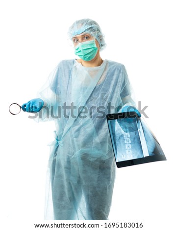 Laboratory Assistant, Doctor. A medic in a disposable medical gown, mask, glasses, hat, gloves, studies an x-ray and examines it through a magnifying glass. isolated