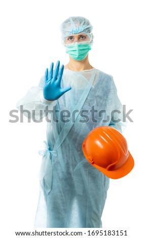 Laboratory assistant, a doctor in protective medical clothing holds a construction helmet and shows a stop sign, class, indicates a helmet. isolated