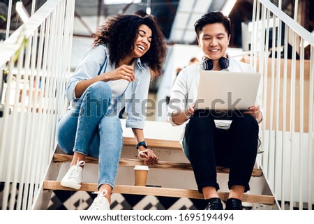 Charming girl and handsome guy watching funny video on notebook and laughing stock photo
