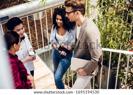 Handsome young man with laptop and cellphone talking with friends stock photo