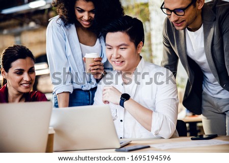 Cheerful men and women watching funny video on notebook stock photo