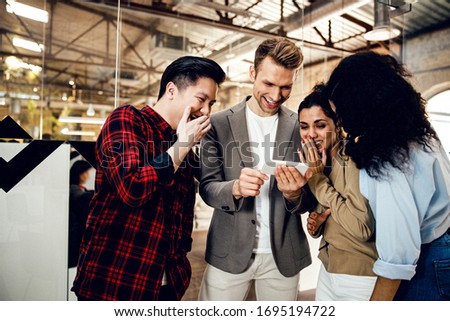 Joyful business colleagues using smartphone and smiling stock photo