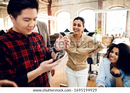 Handsome man using smartphone while ladies looking at him and smiling stock photo