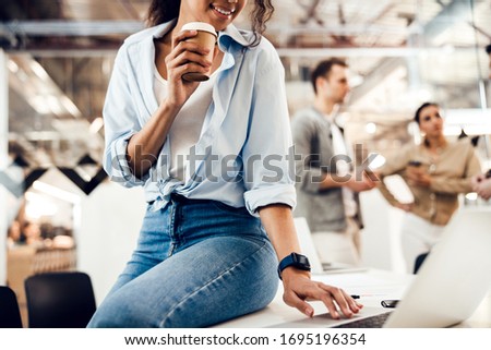 Smiling Afro American woman holding coffee cup and working on notebook stock photo
