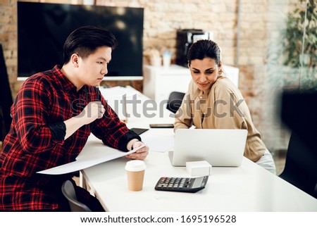 Male worker holding mock up placard while smiling young woman using laptop stock photo