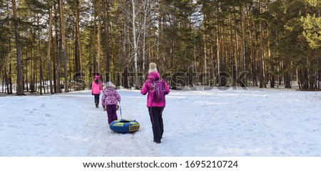 Children with pipes walk through the woods. Tubing in the winter forest.
