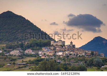 Hilltop Village in Cevennes valley landscape near Le Rozier with mountains and hills under colorful sky Royalty-Free Stock Photo #1695212896