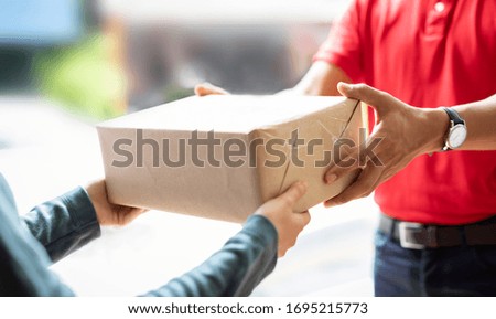 Hands woman receiving parcel from hands delivery man at the door at home.