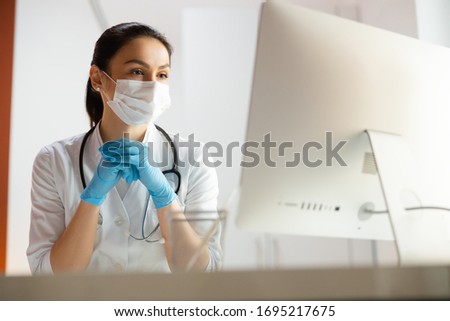 Serious pediatrician in medical mask doing her job at workplace stock photo. Pediatrics concept