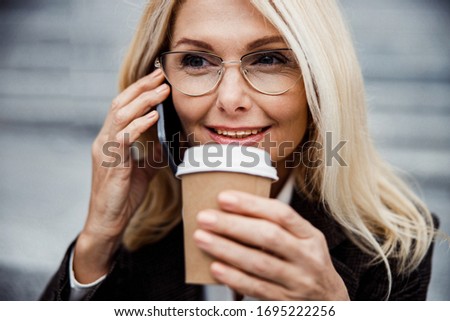 Closeup portrait of a smiling elegant Caucasian woman holding a disposable cup in her hand