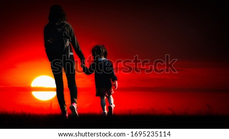 Mother and daughter walking on the field with sunset