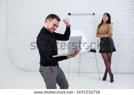 A smiling businessman is standing with a laptop while a woman is writing a business plan on a white board. Stand on a white background.