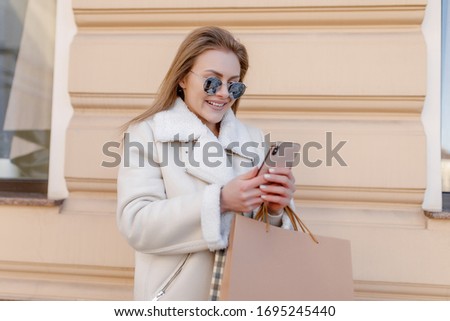 Photo of young business and  fashionable woman with shopping bags walking in the city and  smiling.