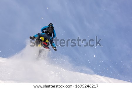 an elite snowmobiler is testing a new model of mountain snowmobile, the prototype of 2021. jump and ride in a big avalanche on a snowmobile. bright snowmobile and suit without brands. Winter extreme