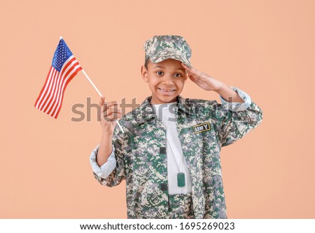 Little saluting African-American soldier with USA flag on color background