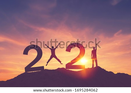 Man raise hand up and man jumping on sunset sky at top of mountain and number like 2021 abstract background. Happy new year and holiday celebration concept. Vintage tone filter effect color style. Royalty-Free Stock Photo #1695284062