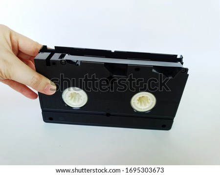 Hand holding a Video Cassette. Image of the old black video tape VHS(video home system) isolated on white background.