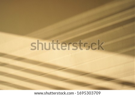 Shadows of straight lines that make an angular geometry on sugar cookie colored walls.