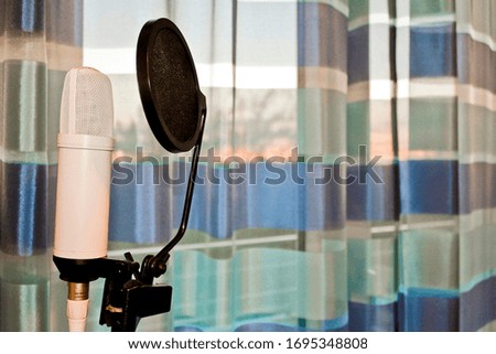 White microphone with pop protection in blue surroundings and sunset. Leherheide, Bremerhaven, Germany.