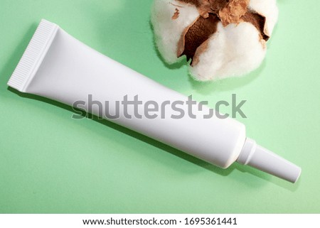 White tube for cosmetics isolated on a green background. White bottle for cream. Beauty and health concept.
