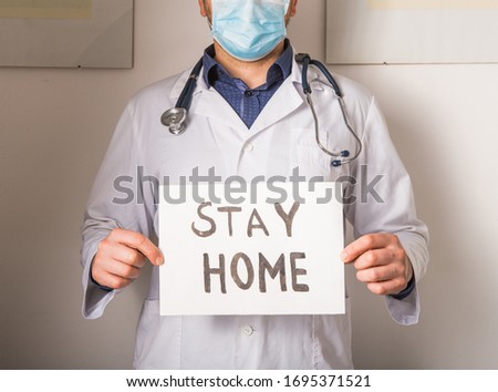 Doctor holding STAY HOME sign. Begging People with hashtag #StayHome to Fight Coronavirus. Anti nCoV Covid-19 Virus Royalty-Free Stock Photo #1695371521