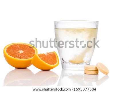 Series of orange flavored vitamin c effervescent tablet dropped and dissolve in glass of water on white background