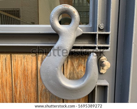 Large gray metal hook on the front door as decorative element, decorative grey hook on the door close up