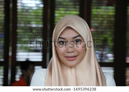 Young asian malay man woman with headscarf stand confident look at camera man sit behind at rustic cafe table
