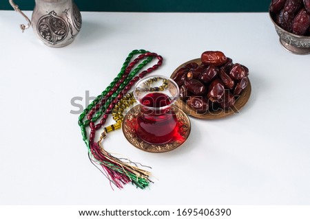 Dry medjoul dates in a vintage bowl with turkish tea in a glass. Close up.