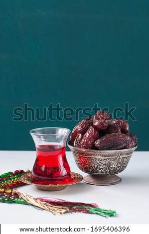 Dry medjoul dates in a vintage bowl with turkish tea in a glass. Close up.