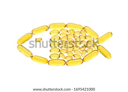 Transparent yellow medical capsules in fish shape, isolated on white background. Top view, health and care concept