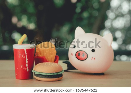 Toy fast food food and drink with toy pink on wood table. Concept of unhealthy food