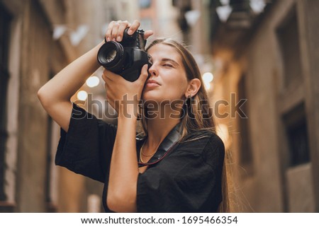 Blonde woman is taking photos of the city, she works for city magazine and received an order for a couple of pictures representing all attractive views of the city, she uses her professional equipment