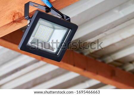 LED flood light, spot light on the top of the roof. Powerful construction lighting floodlight a lantern for illumination of a local area at night Royalty-Free Stock Photo #1695466663