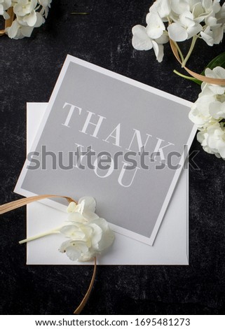 A floral touch makes this thank you note an elegant thank you to a wedding or shower invitation with classy combination of gentle white blossoms on black background