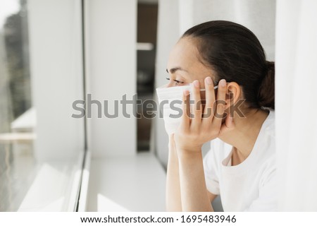 Tired doctor in medical mask looking through window. Important job and self isolation during coronavirus pandemic. Hope for medicine. Royalty-Free Stock Photo #1695483946