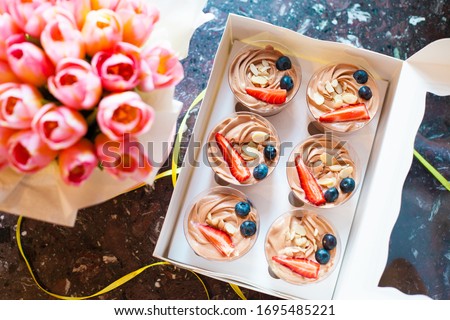 Box of choco mini cakes with berries on dark marble background