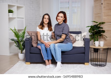happy mother and daughter sitting in living room