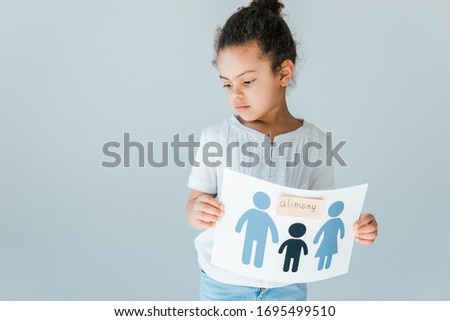 upset african american child holding paper with drawn family and alimony lettering isolated on white
