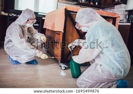 Specialists in protective suits take samples from surfaces in the home to test for a new corona virus.