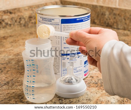 Mother prepares baby milk formula in kitchen