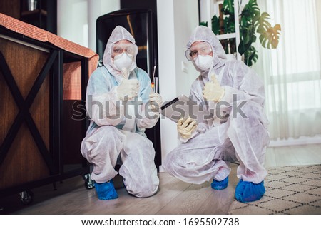 Specialists in protective suits take samples from surfaces in the home to test for a new corona virus.