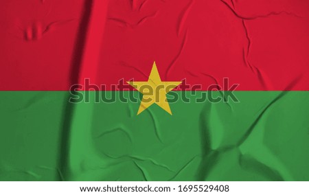 Burkina Faso flag on crumpled paper background.
